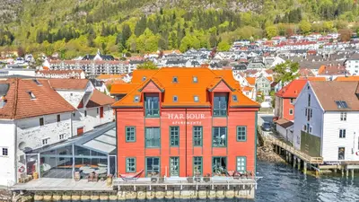 an orange building on the water in a city at Heimby - Roomy Studio w Free parking and SeaView in Bergen