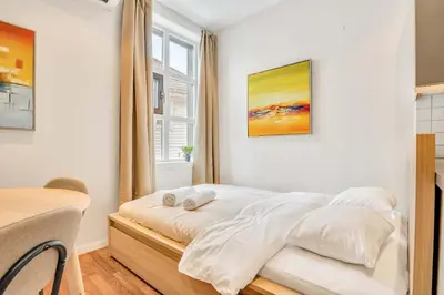 a bedroom with a bed with white sheets and a window at Heimby - Roomy Studio w Free parking and SeaView in Bergen