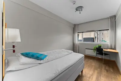 a white bedroom with a bed and a desk at Dølaheimen in Lillehammer