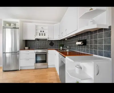 a kitchen with white cabinets and stainless steel appliances at 2BR, 2 parking spots, EV-charger and home office in Trondheim