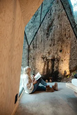 a woman sitting in a window reading a book at Spectacular Fjord getaway - The Forge in Leirgulen