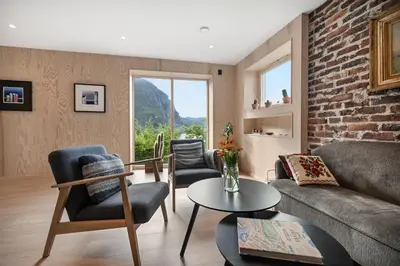 a living room with a couch and chairs and a brick wall at Spectacular Fjord getaway - The Forge in Leirgulen