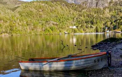 a boat sitting on the shore of a lake at Awesome Home In Sævareid With Lake View in Sævareid