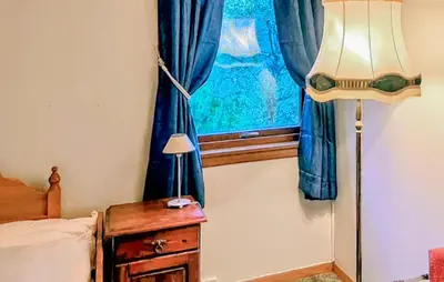 a bedroom with a bed and a lamp and a window at Awesome Home In Sævareid With Lake View in Sævareid