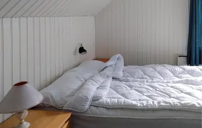 a large white bed in a room with a lamp at Awesome Home In Sævareid With Lake View in Sævareid