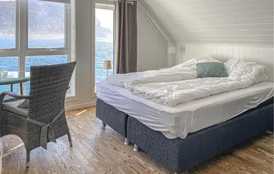 a bed in a room with a table and a chair at 3 Bedroom Awesome Home In Gursken in Larsnes