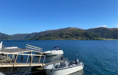 two boats are docked at a dock on a lake at 3 Bedroom Awesome Home In Gursken in Larsnes