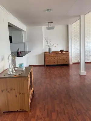 an empty living room with a kitchen and wooden floors at Seljesanden Apartment in Selje