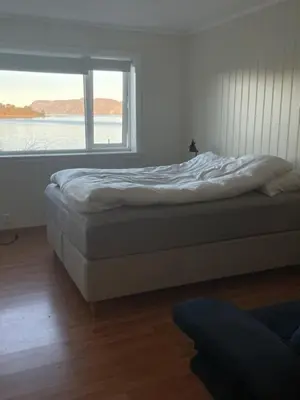 a bed in a room with a large window at Seljesanden Apartment in Selje
