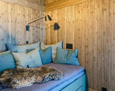 a bed with blue pillows in a room with wooden walls at Modern Cabin By The Ski Trails At Fagerhøy in Sør-Fron