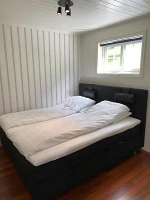 a bed with a black frame in a room with a window at Sea Front Olden in Olden