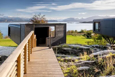 a wooden walkway leading to a building with a door at Torvika Seaview Pods in Bølandet