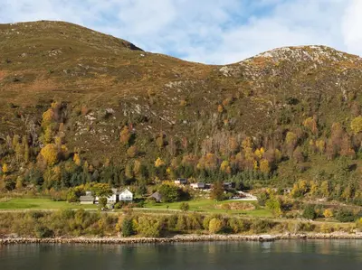 a house on the shore of a lake with a mountain at Torvika Seaview Pods in Bølandet