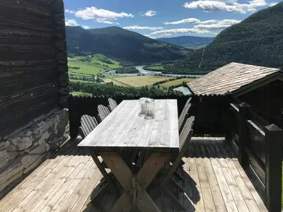 a wooden table on a deck with a view of a valley at Farm In The Heart Of Gudbrandsdalen in Kvam