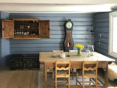 a dining room with a table and a clock on the wall at Farm In The Heart Of Gudbrandsdalen in Kvam
