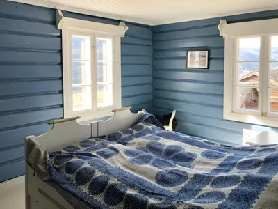 a bedroom with blue walls and a bed with a comforter at Farm In The Heart Of Gudbrandsdalen in Kvam