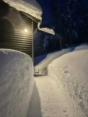 a pile of snow in front of a house with a light at Floating Dream Cabin Embraced By Nature in Sogndal