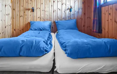 two beds with blue pillows next to a wooden wall at Gorgeous Home In Vøringsfoss With Sauna in Maurset