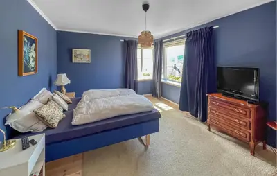 a blue bedroom with a bed and a tv at 2 Bedroom Nice Apartment In Lillehammer in Lillehammer