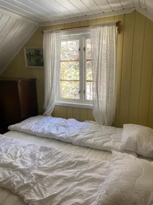 an unmade bed in a bedroom with a window at Huset Utsikten på Langsjøvolden gård in Tolga