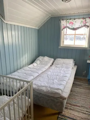 a bedroom with a bed and a window and a crib at Huset Utsikten på Langsjøvolden gård in Tolga