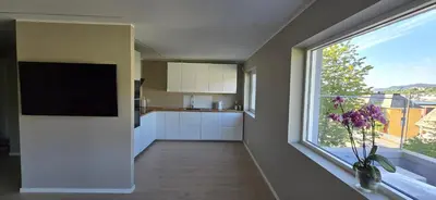 a kitchen with white cabinets and a large window at Modern house in Bergen