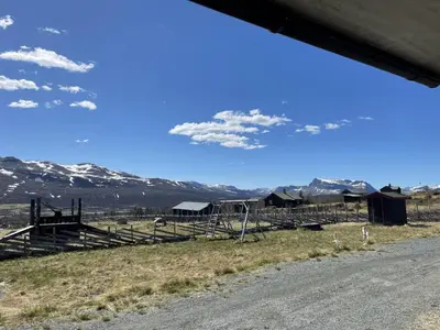 a view of a farm with mountains in the background at Syndinstøga in Ryfoss