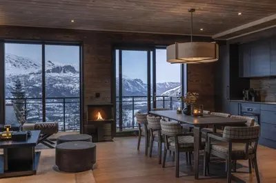 a kitchen with a table and chairs and a fireplace at New and exclusive chalet apartment with mountain panorama view in Tuv