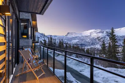 a balcony with a chair and a view of snow covered mountains at New and exclusive chalet apartment with mountain panorama view in Tuv