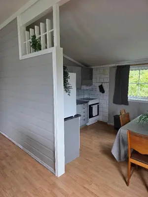 a living room with a white wall and a kitchen at Hardanger Fjord Living in Vossevangen