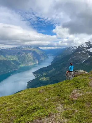 a woman sitting on top of a mountain overlooking a lake at Hardanger Fjord Living in Vossevangen
