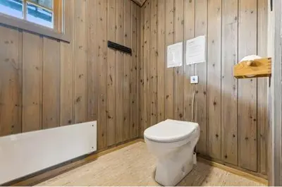 a wooden bathroom with a toilet and a bath tub at Guest favorite - 5 mins from Vøringsfossen in Garden