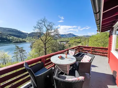 a table and chairs on a balcony with a view of a river at Holiday Home Tussebu by Interhome in Gripne