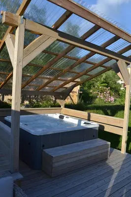 a wooden deck with a hot tub under a wooden roof at Charming farmhouse with jacuzzi and patio in Stryn