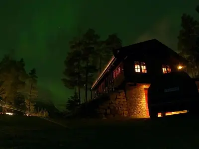 a log cabin at night with the lights on at Holiday cabin, Kristianplass at Bjorli, Lesja in Bjorli