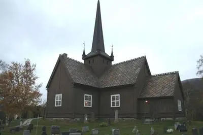 a large wooden church with a steeple in a cemetery at Holiday cabin, Kristianplass at Bjorli, Lesja in Bjorli
