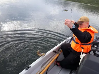 a man on a boat with a fish in the water at Haukeli Hotel in Haukeligrend