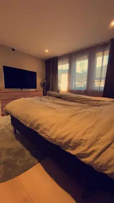 a bedroom with a large bed and a flat screen tv at Penthouse apartment with sauna, balcony and free coffe in Bergen