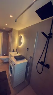 a bathroom with a shower and a washing machine at Penthouse apartment with sauna, balcony and free coffe in Bergen