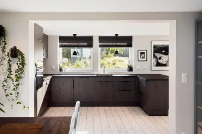 a kitchen with brown cabinets and a sink and two windows at Kvitsand Ocean Castle in Hitra