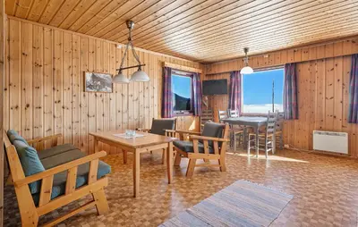 a living room with wooden walls and tables and chairs at Awesome Home In Vøringsfoss With Sauna in Maurset