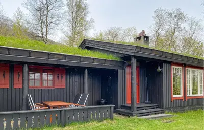 a black house with a grass roof with a table and chairs at 2 Bedroom Lovely Home In Oppdal in Oppdal