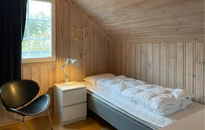 a bed in a wooden room with a lamp and a chair at Stunning Home In Bjorli With Wifi in Bjorli