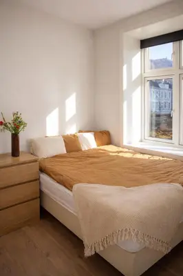 a white bedroom with a bed and a window at Central apartment in Bergen