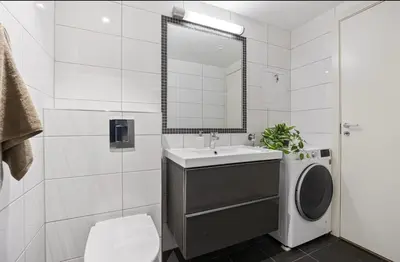 a bathroom with a sink and a washing machine at Central apartment in Bergen