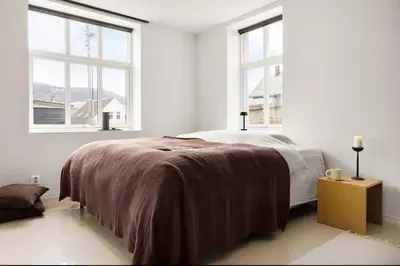 a white bedroom with a bed and two windows at Sentral leilighet, Bergen in Bergen