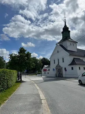 a large white building with a tower on a road at Sentral leilighet, Bergen in Bergen