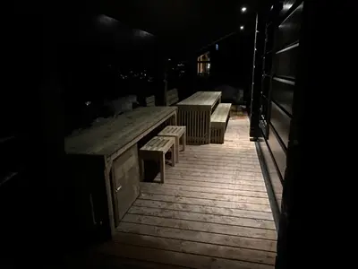 a table and benches on a deck at night at Exclusive Fjord Lodge with Private Jacuzzi and Epic Views in Lii