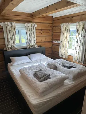 a large bed in a wooden room with windows at Lekker tømmerhytte in Tyinkrysset