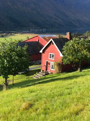 a red house in a field of green grass at Historic Farmhouse In Scenic Isfjorden in Isfjorden